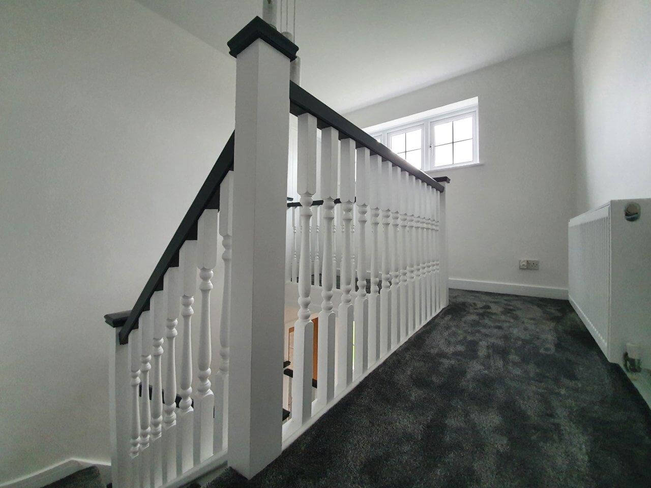 A hallway, stairwell and landing after being decorated, striking black and white